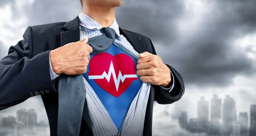 Man wearing a suit with a superhero shirt underneath with a heart beat image on it