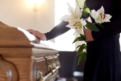 person at a funeral touching the casket